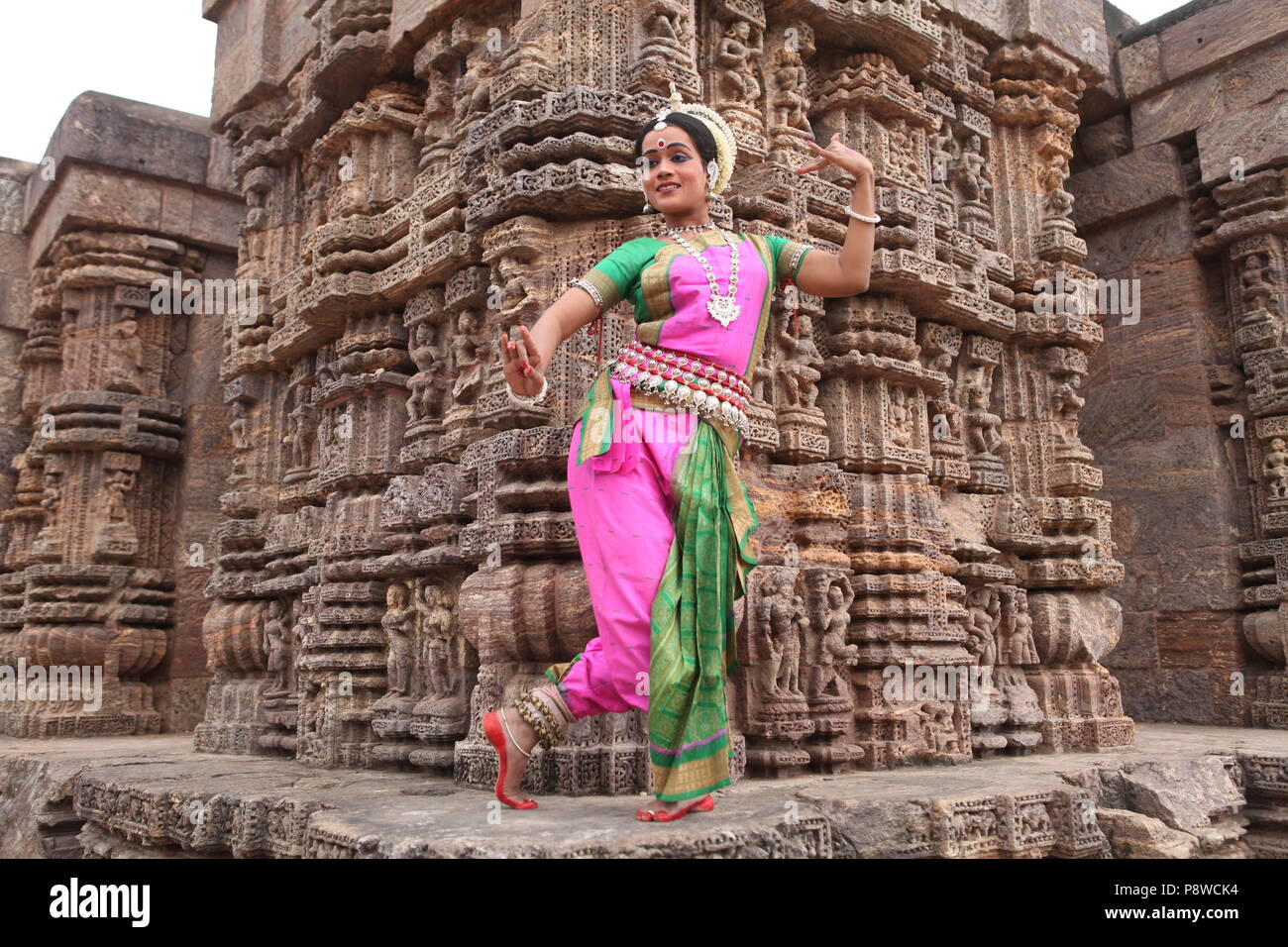 odissi is one of the eight classical dance forms of india,from the state of odisha.here the dancer poses before temples with sculptures Stock Photo