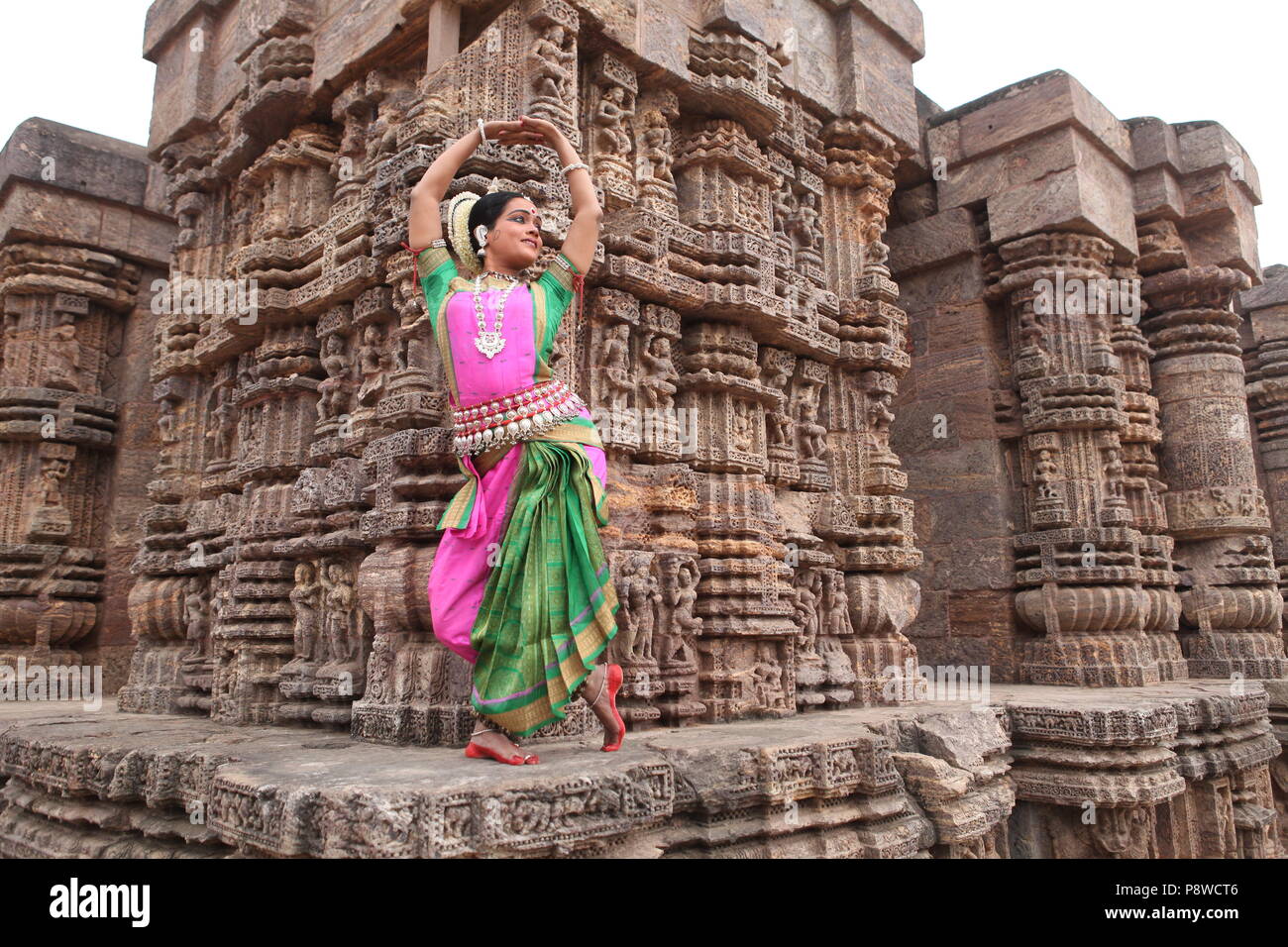 odissi is one of the eight classical dance forms of india,from the state of odisha.here the dancer poses before temples with sculptures Stock Photo