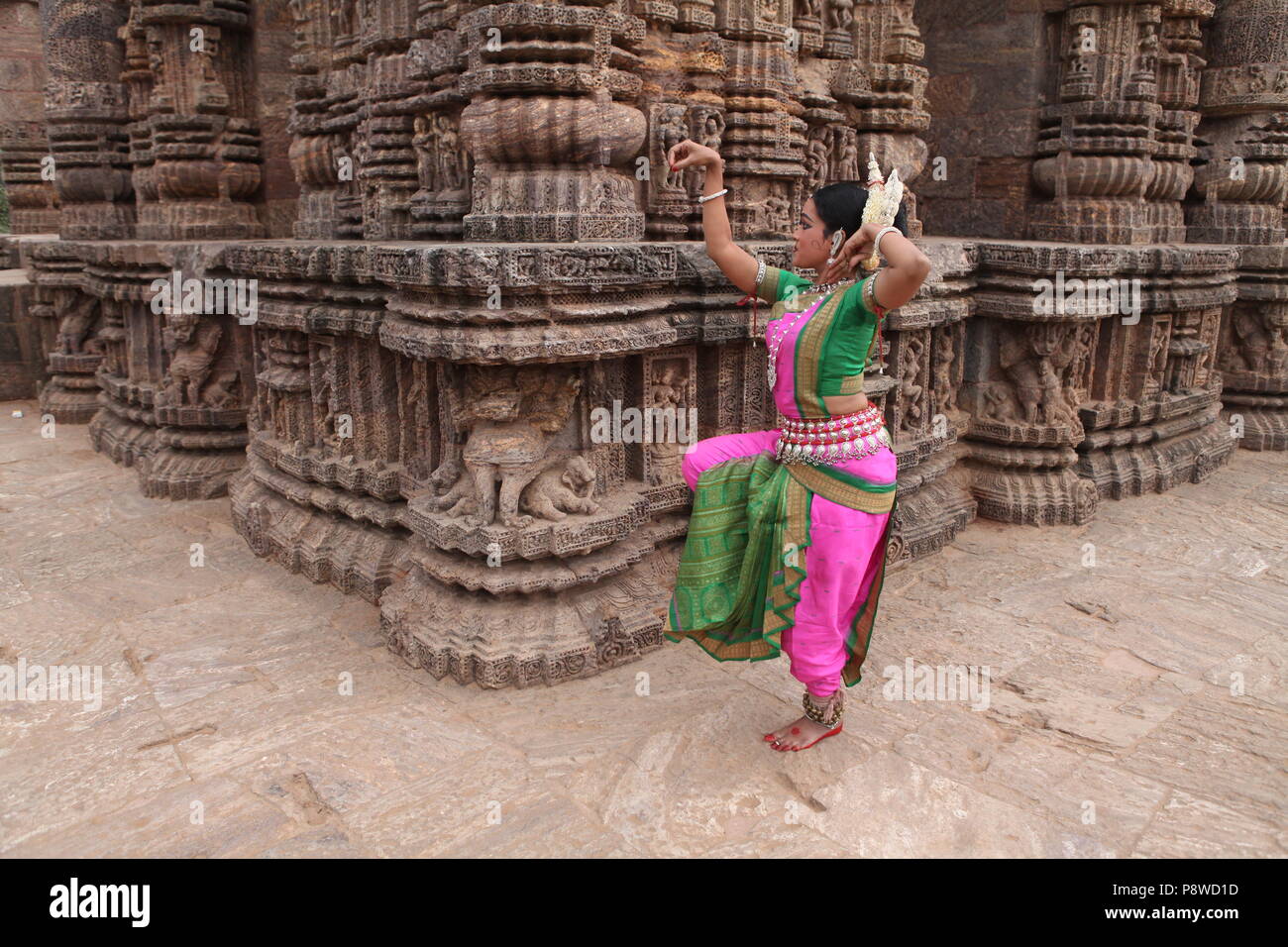 odissi is one of the eight classical dance forms of india,from the state of odisha.here the dancer poses before temples with sculptures Stock Photo