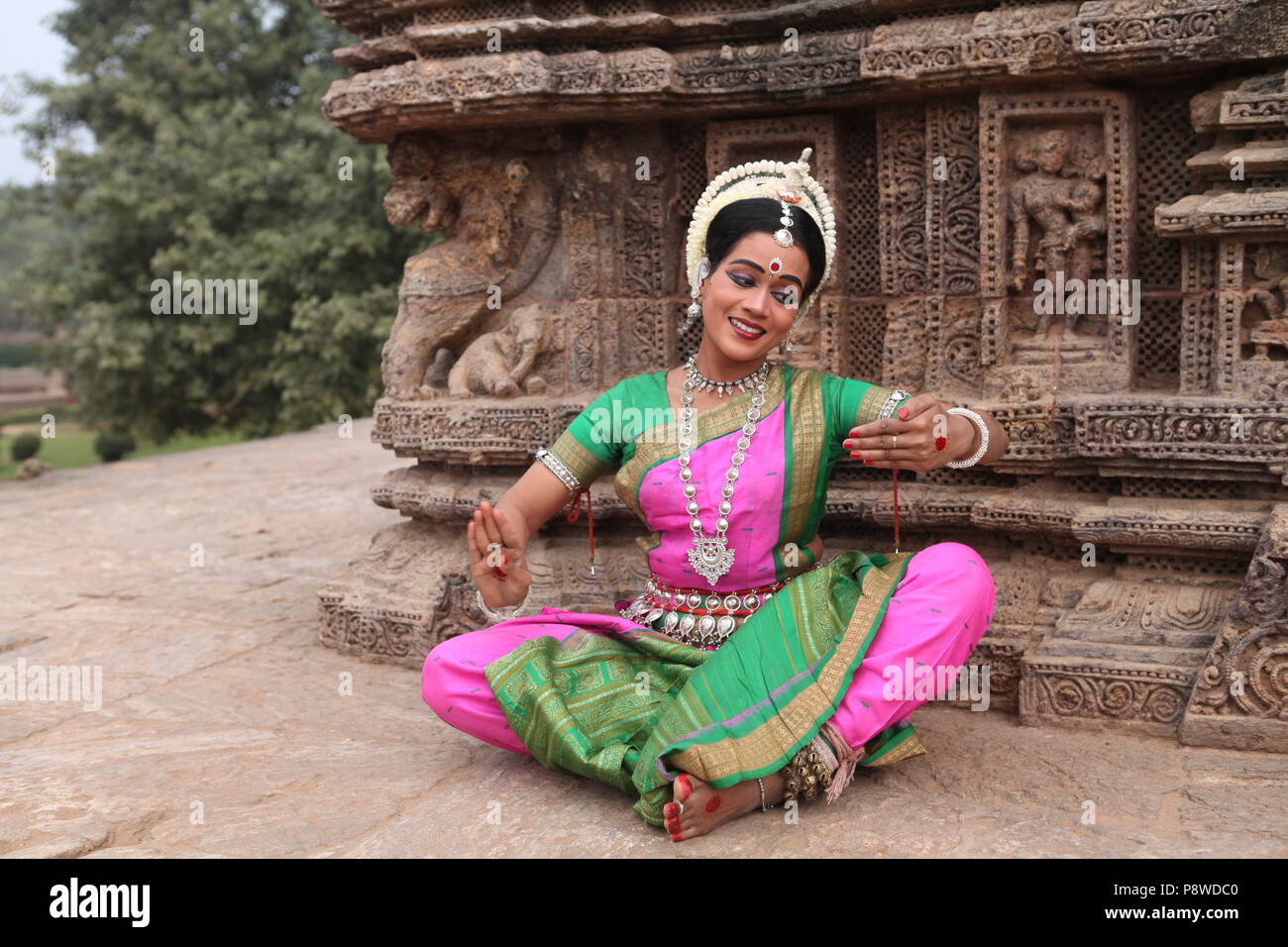 odissi is one of the eight classical dance forms of india,from the state of odisha.here the dancer poses before temples with sculptures Stock Photo