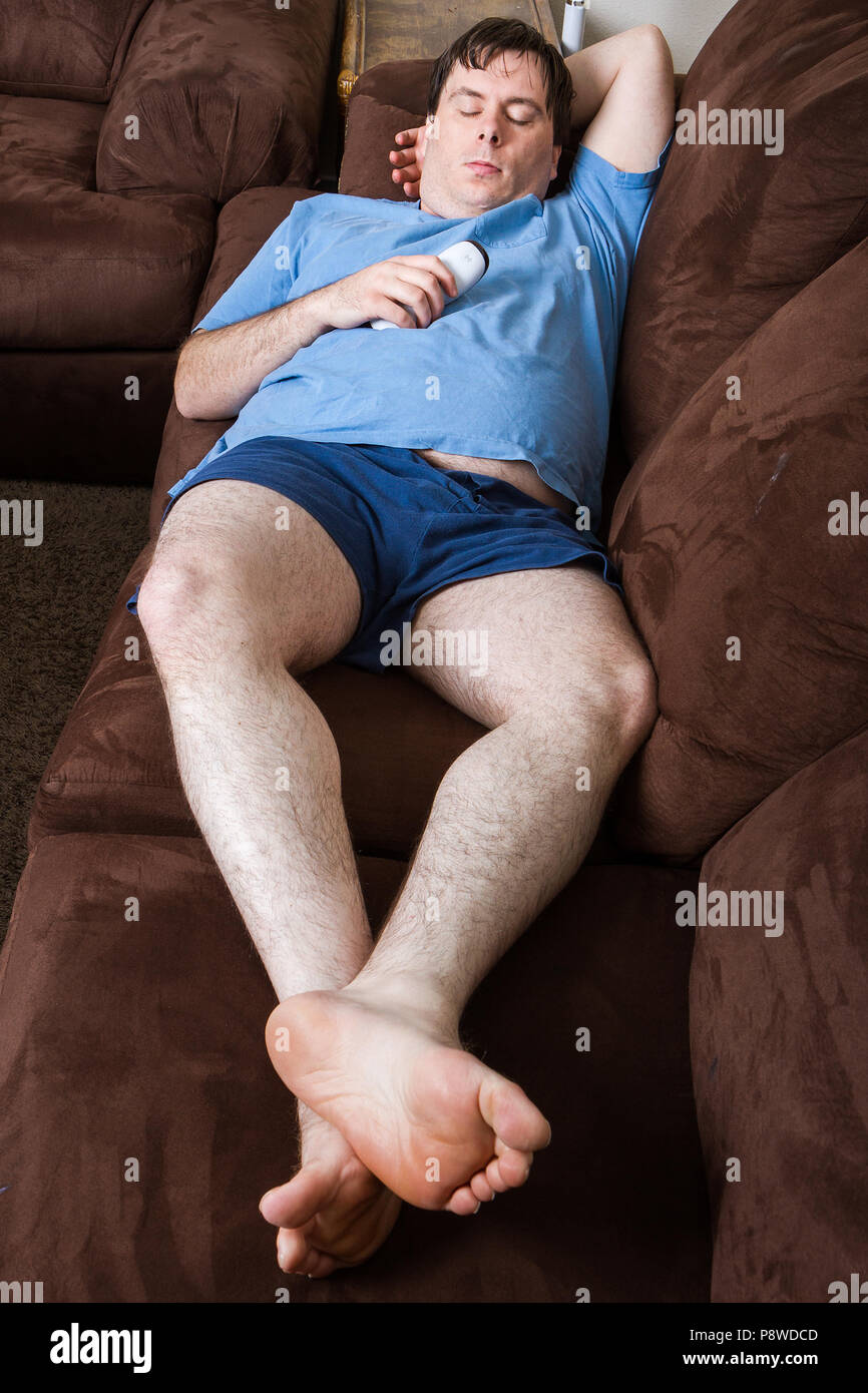 Wide angle view of man laying on couch holding remote Stock Photo