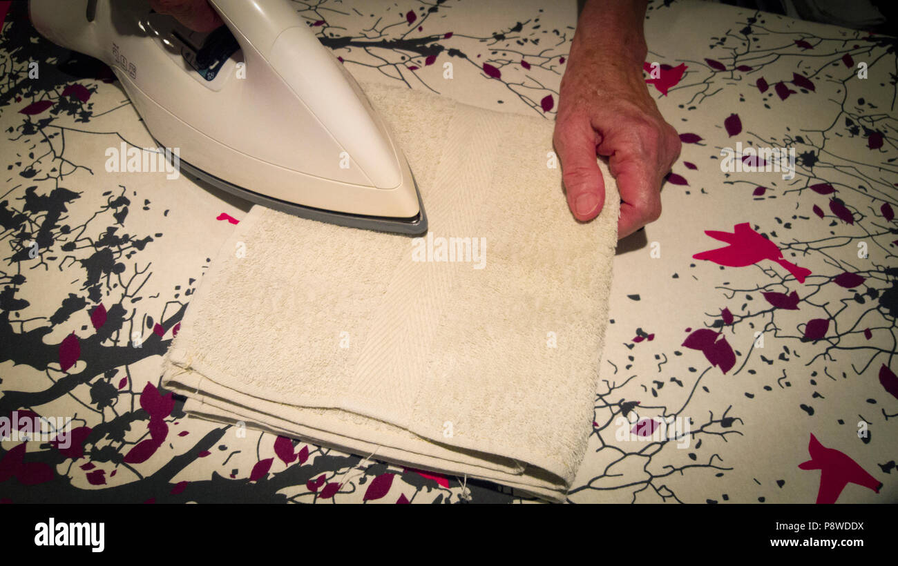 Close up of a woman's hand ironing a bath towel. View from above Stock Photo