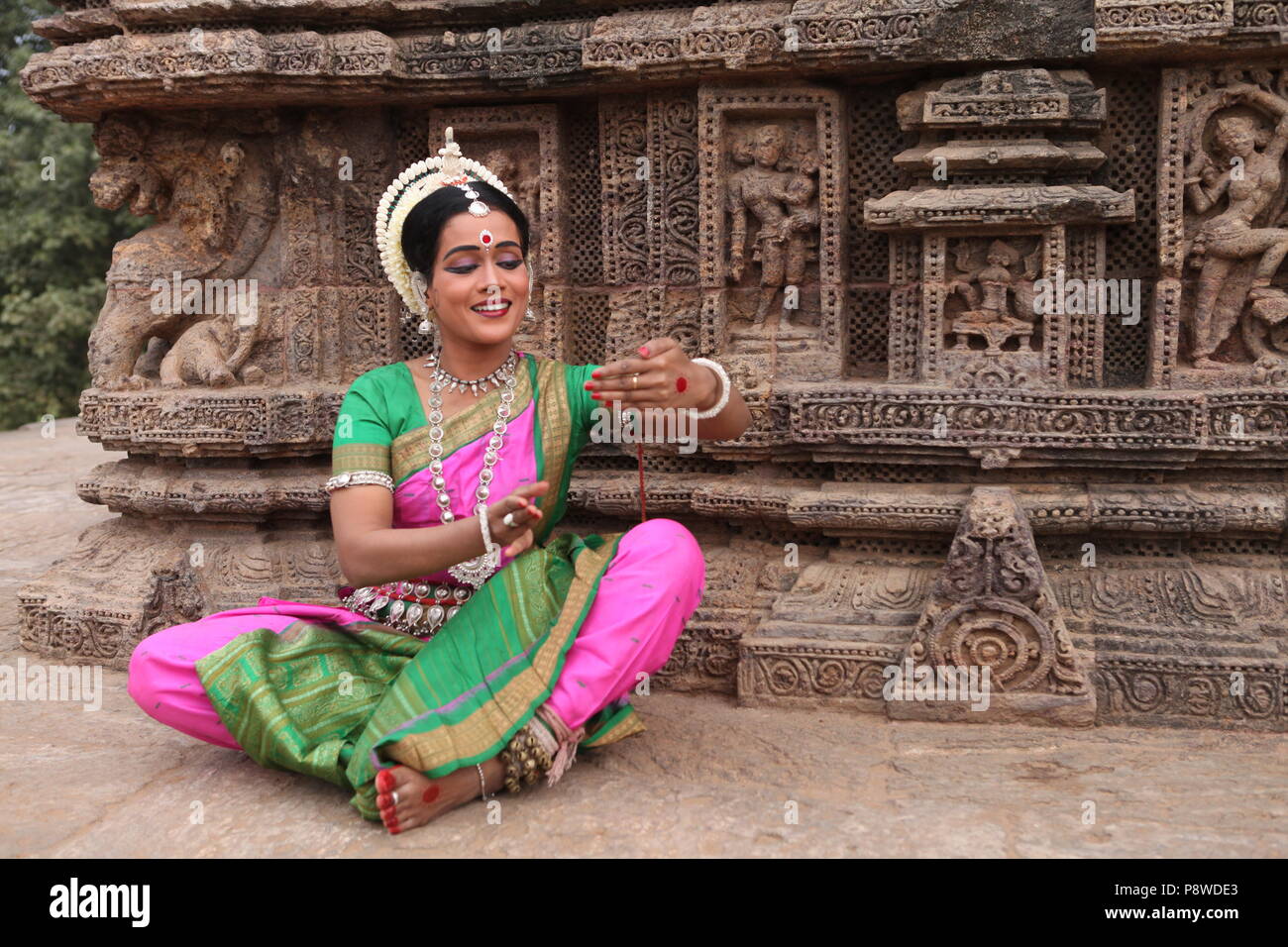 odissi is one of the eight classical dance forms of india,from the state of odisha.here the dancer poses before temples with sculptures Stock Photo