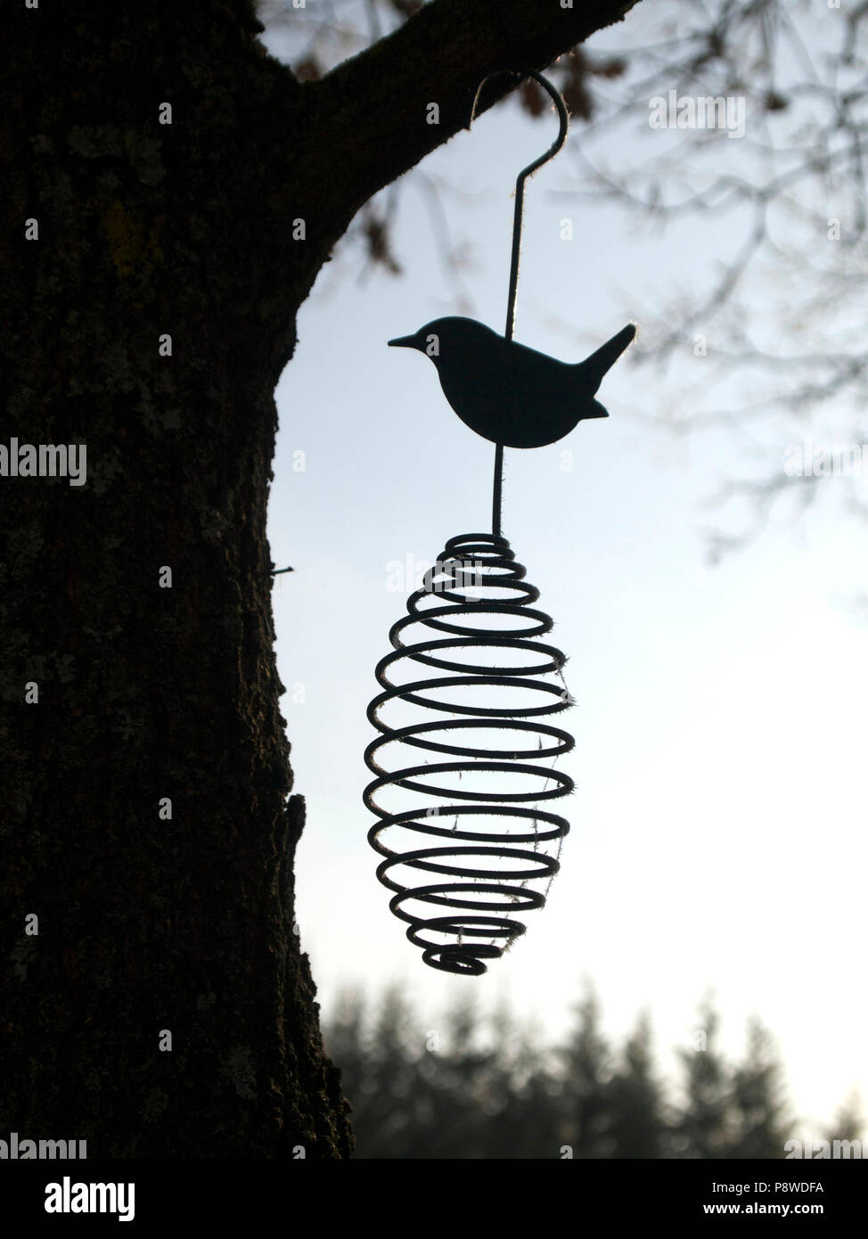 Metal bird ornament hanging from a tree Stock Photo
