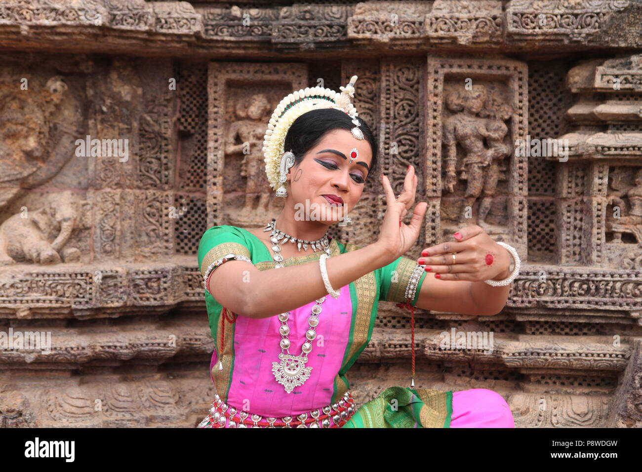 odissi is one of the eight classical dance forms of india,from the state of odisha.here the dancer poses before temples with sculptures Stock Photo