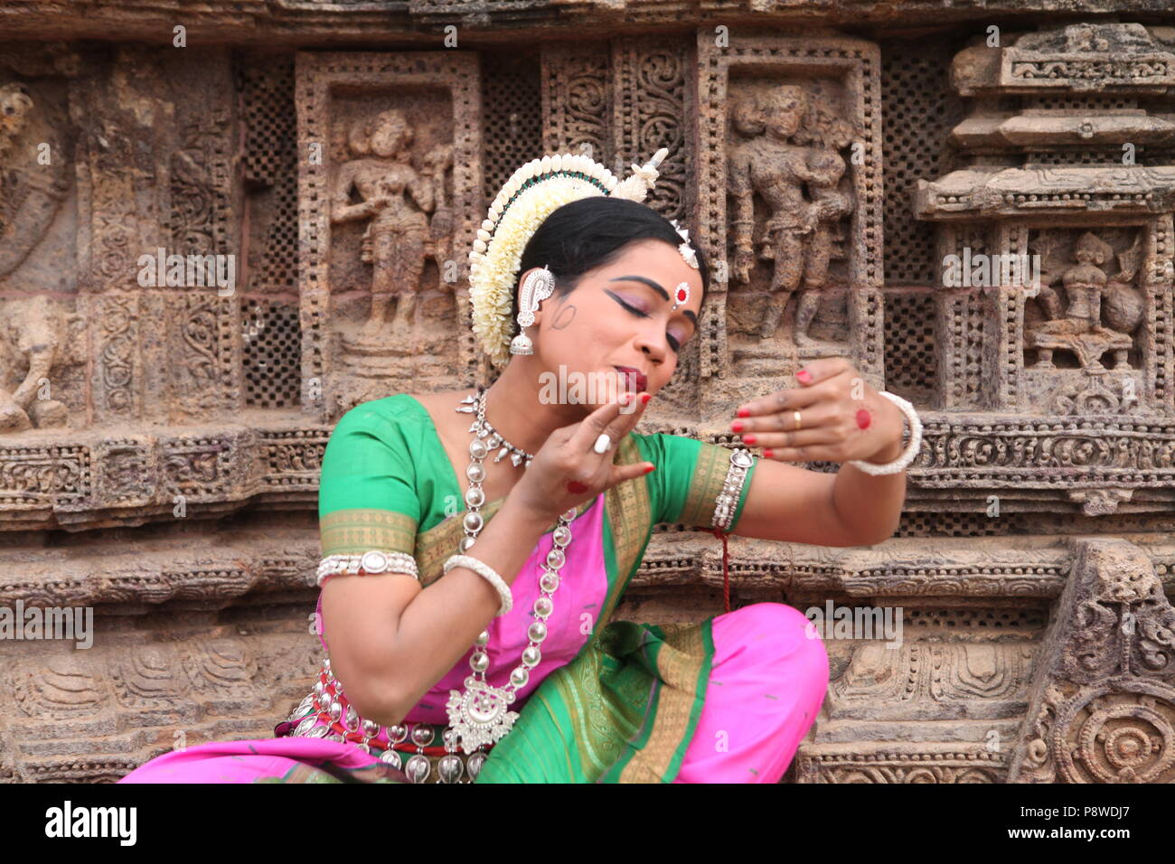 odissi is one of the eight classical dance forms of india,from the state of odisha.here the dancer poses before temples with sculptures Stock Photo