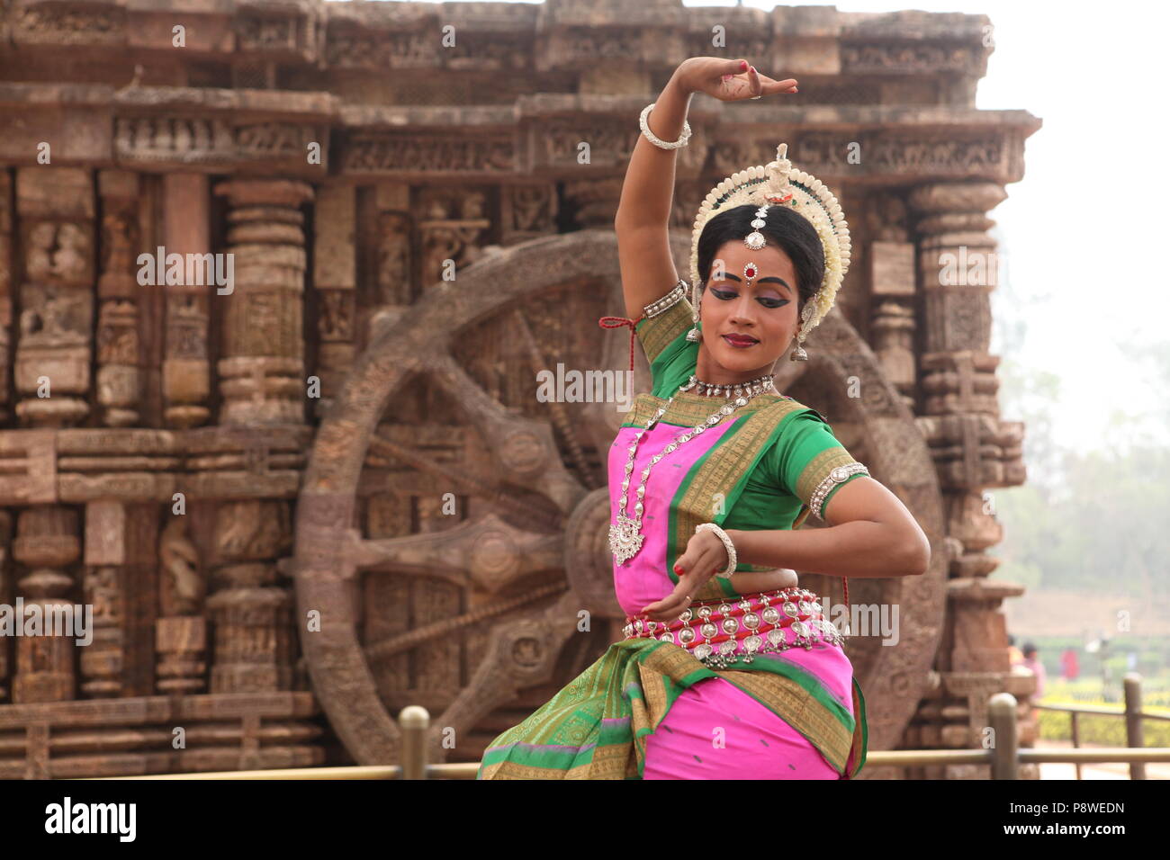 odissi is one of the eight classical dance forms of india,from the state of odisha.here the dancer poses before temples with sculptures Stock Photo