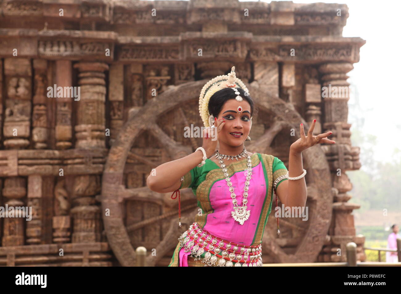 odissi is one of the eight classical dance forms of india,from the state of odisha.here the dancer poses before temples with sculptures Stock Photo
