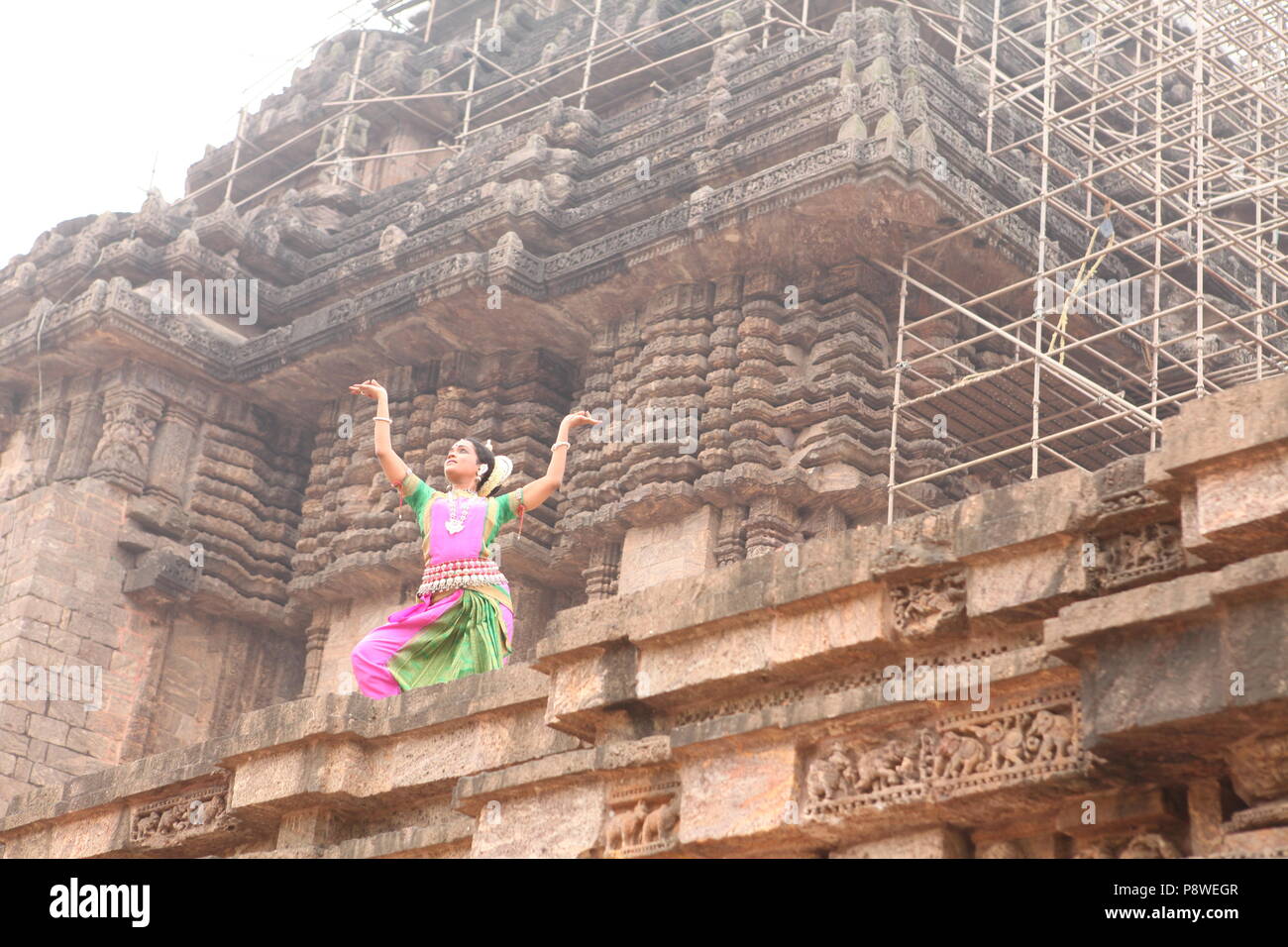 odissi is one of the eight classical dance forms of india,from the state of odisha.here the dancer poses before temples with sculptures Stock Photo