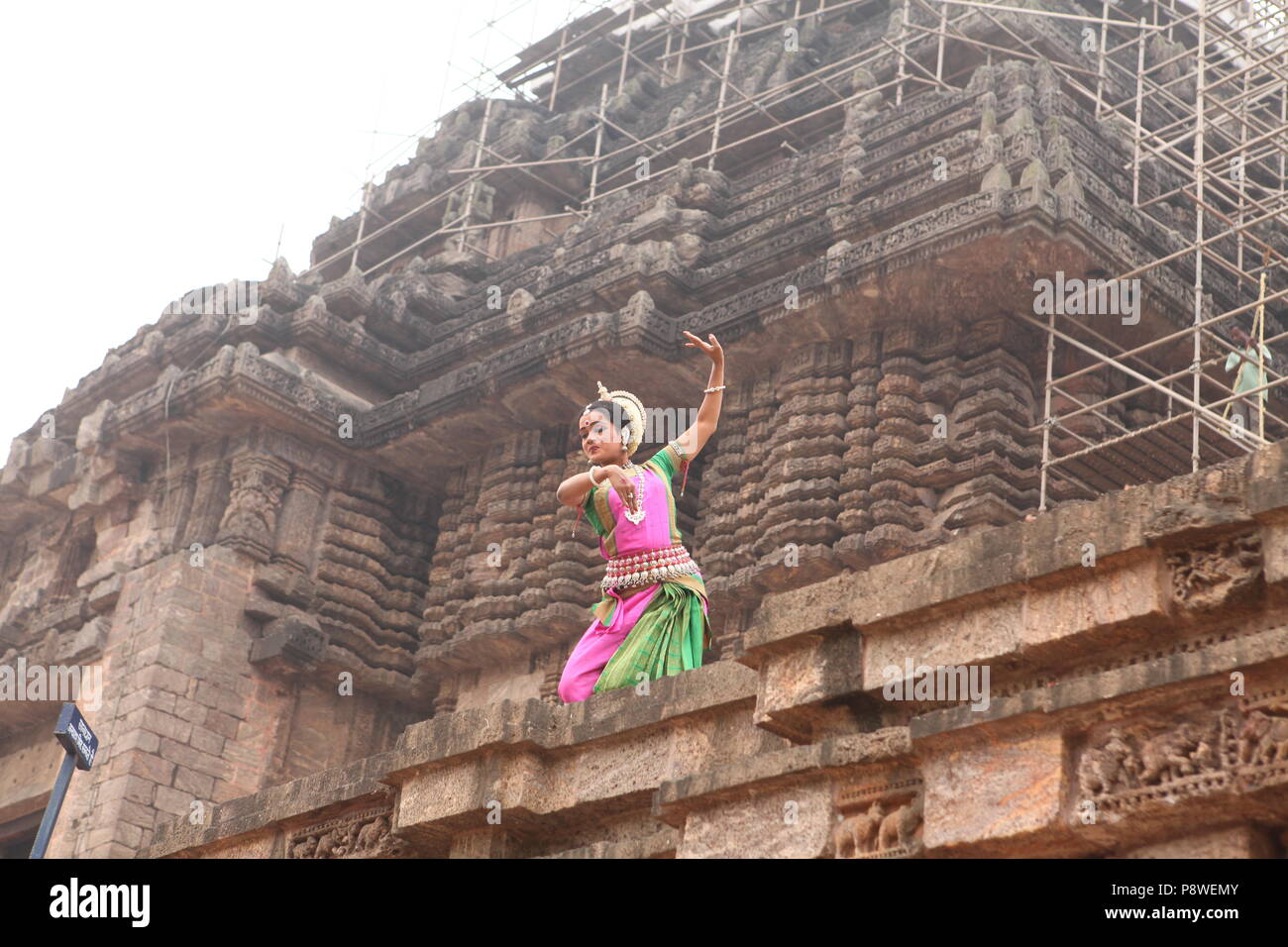 odissi is one of the eight classical dance forms of india,from the state of odisha.here the dancer poses before temples with sculptures Stock Photo