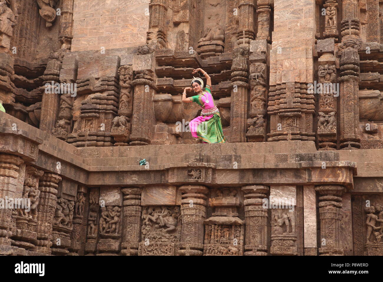 odissi is one of the eight classical dance forms of india,from the state of odisha.here the dancer poses before temples with sculptures Stock Photo