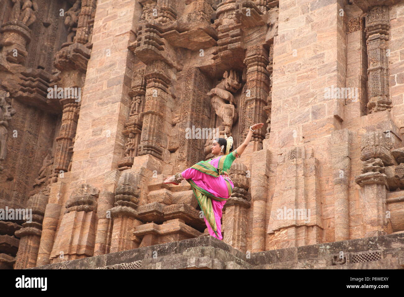 odissi is one of the eight classical dance forms of india,from the state of odisha.here the dancer poses before temples with sculptures Stock Photo