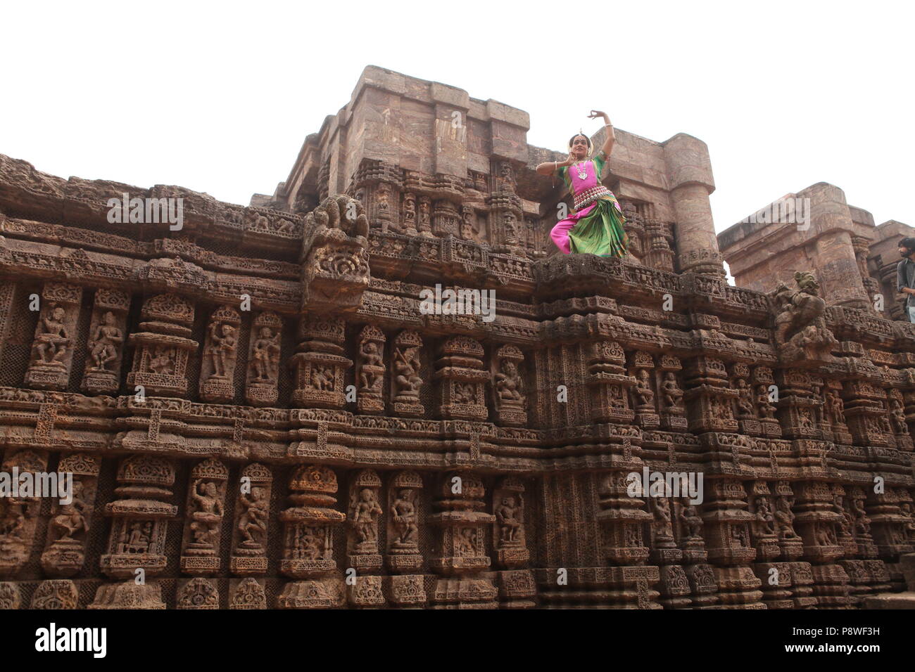 odissi is one of the eight classical dance forms of india,from the state of odisha.here the dancer poses before temples with sculptures Stock Photo