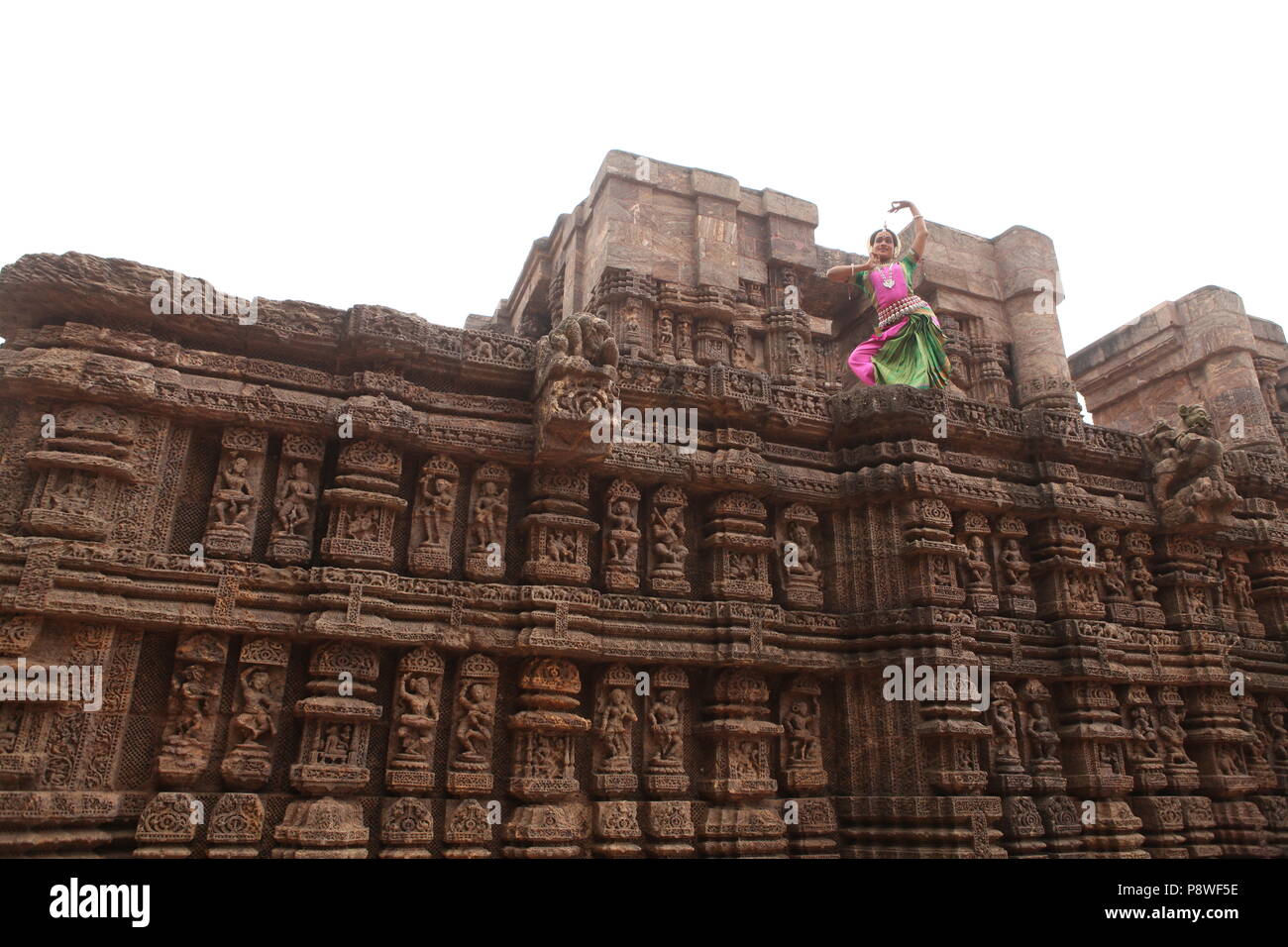 odissi is one of the eight classical dance forms of india,from the state of odisha.here the dancer poses before temples with sculptures Stock Photo