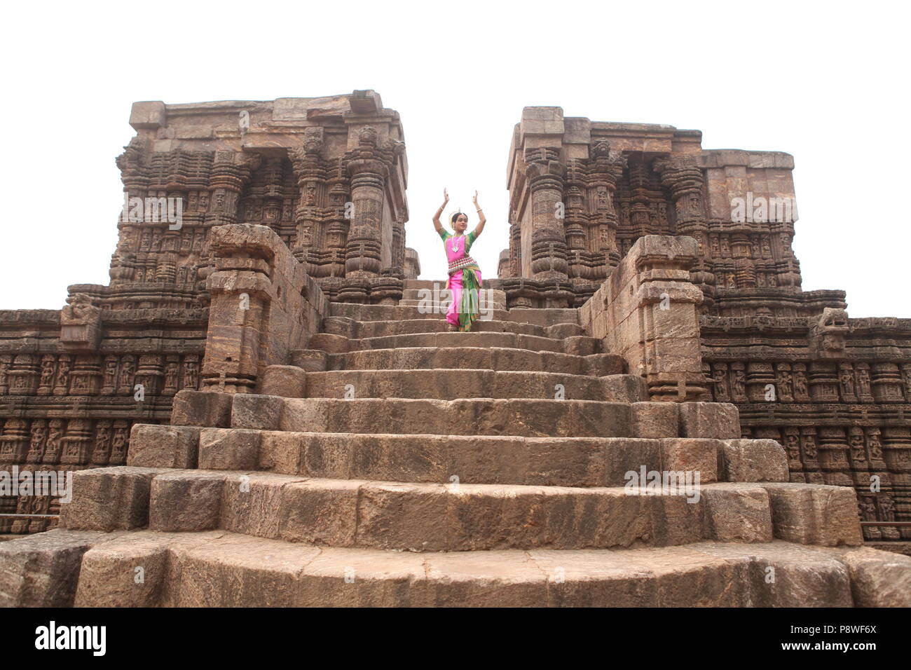 odissi is one of the eight classical dance forms of india,from the state of odisha.here the dancer poses before temples with sculptures Stock Photo