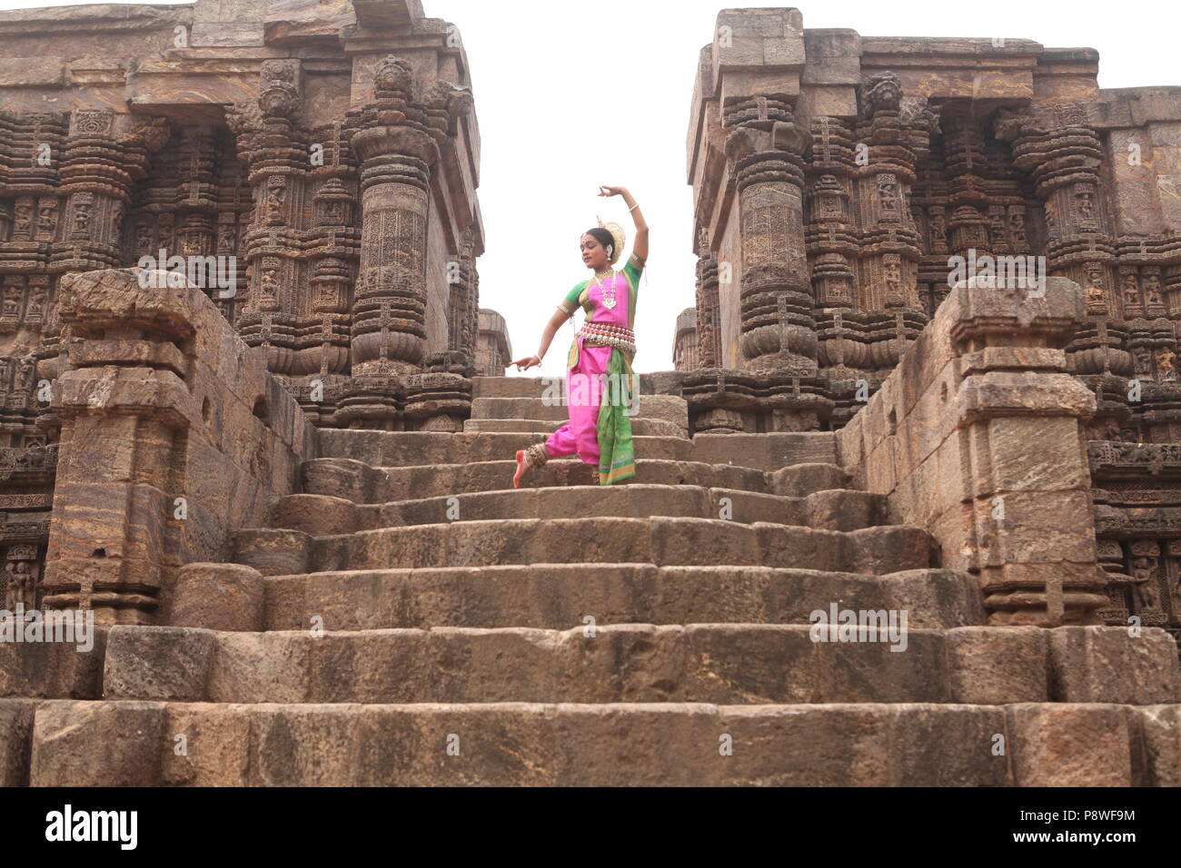 odissi is one of the eight classical dance forms of india,from the state of odisha.here the dancer poses before temples with sculptures Stock Photo