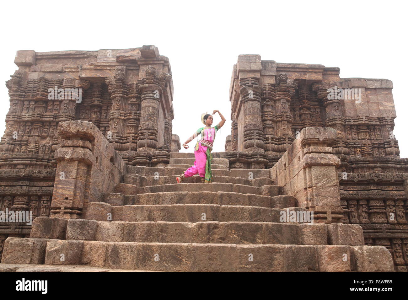 odissi is one of the eight classical dance forms of india,from the state of odisha.here the dancer poses before temples with sculptures Stock Photo