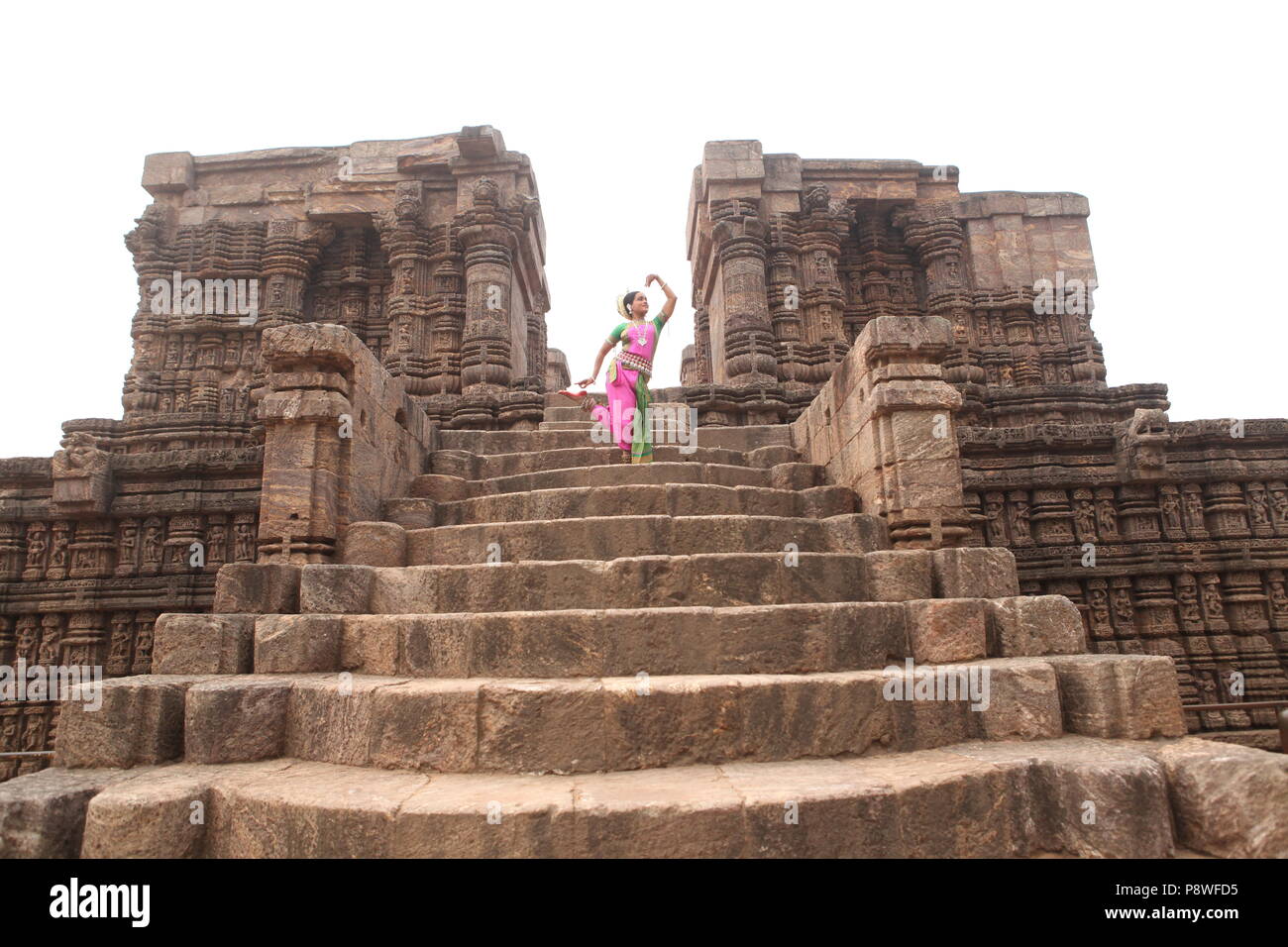 odissi is one of the eight classical dance forms of india,from the state of odisha.here the dancer poses before temples with sculptures Stock Photo