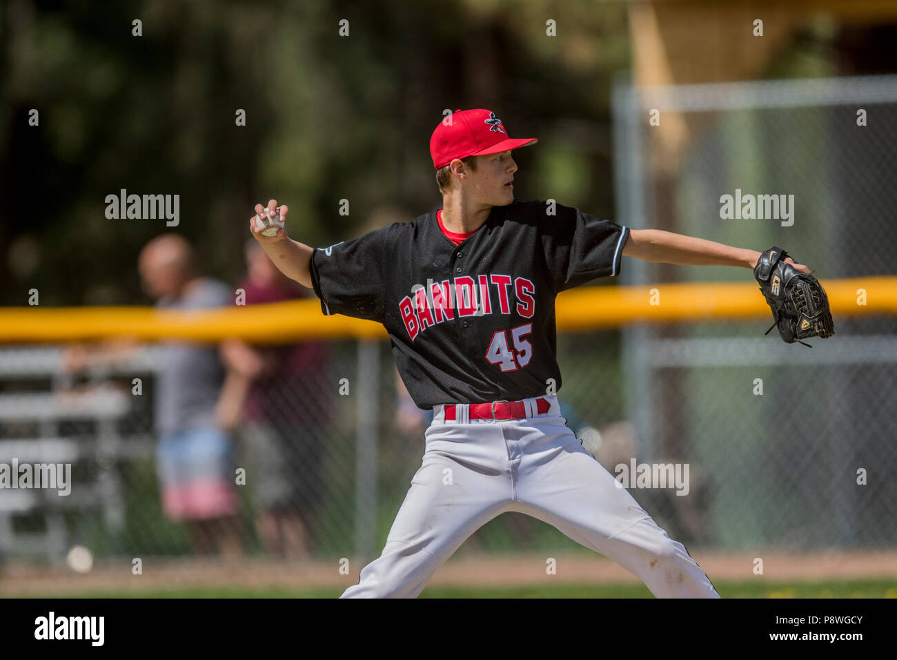 Pitcher delivering pitch, in full stride, showing grip, boys afternoon