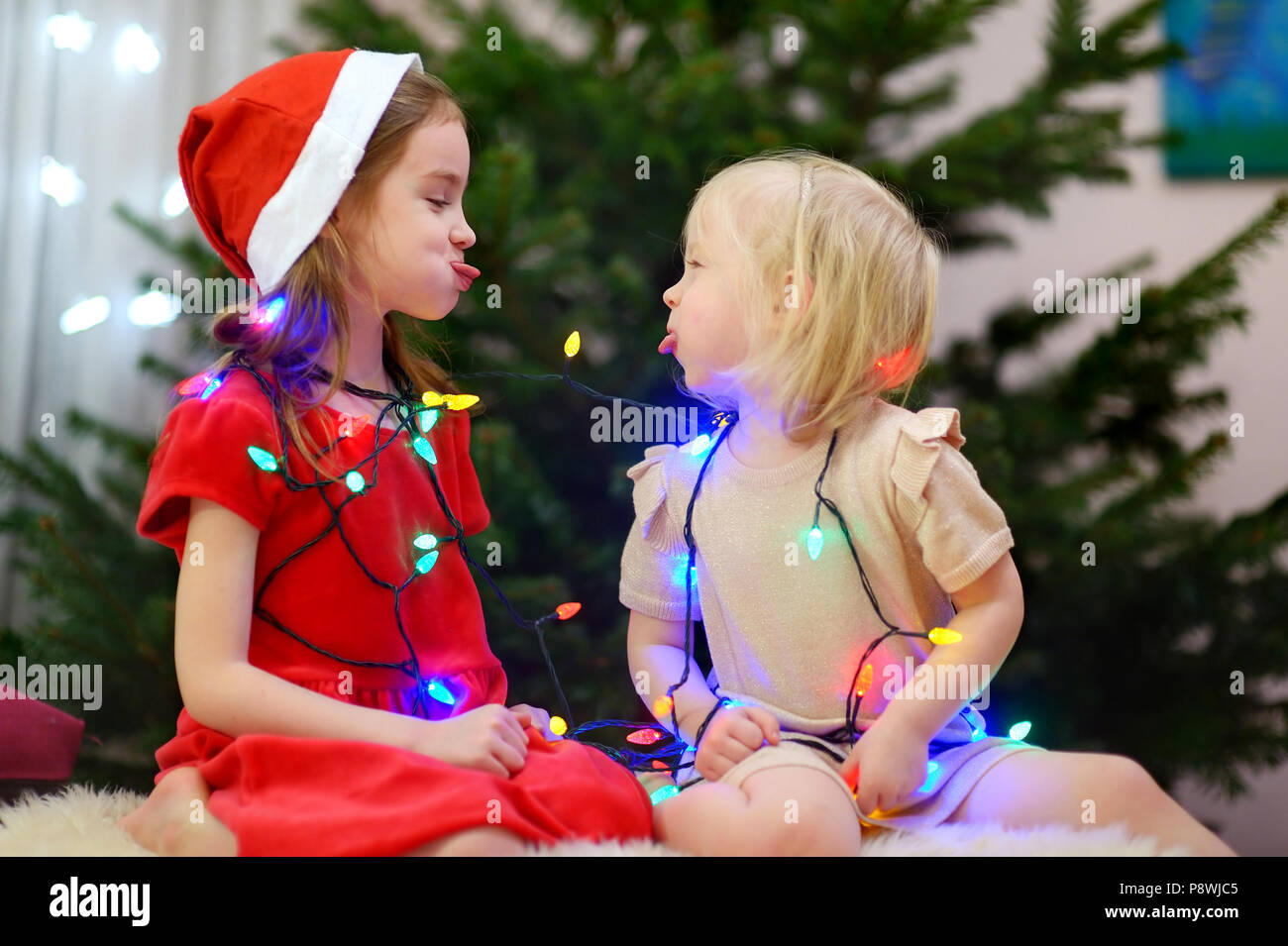 Two adorable little sisters decorating a Christmas tree at home Stock ...