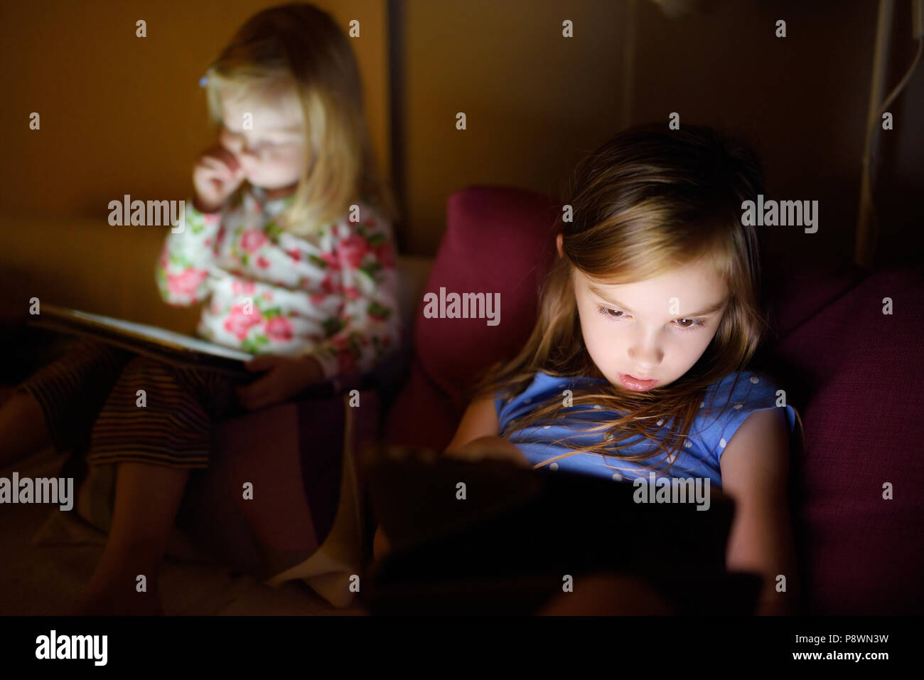 Two little sisters using digital tablet computer in a dark room Stock ...
