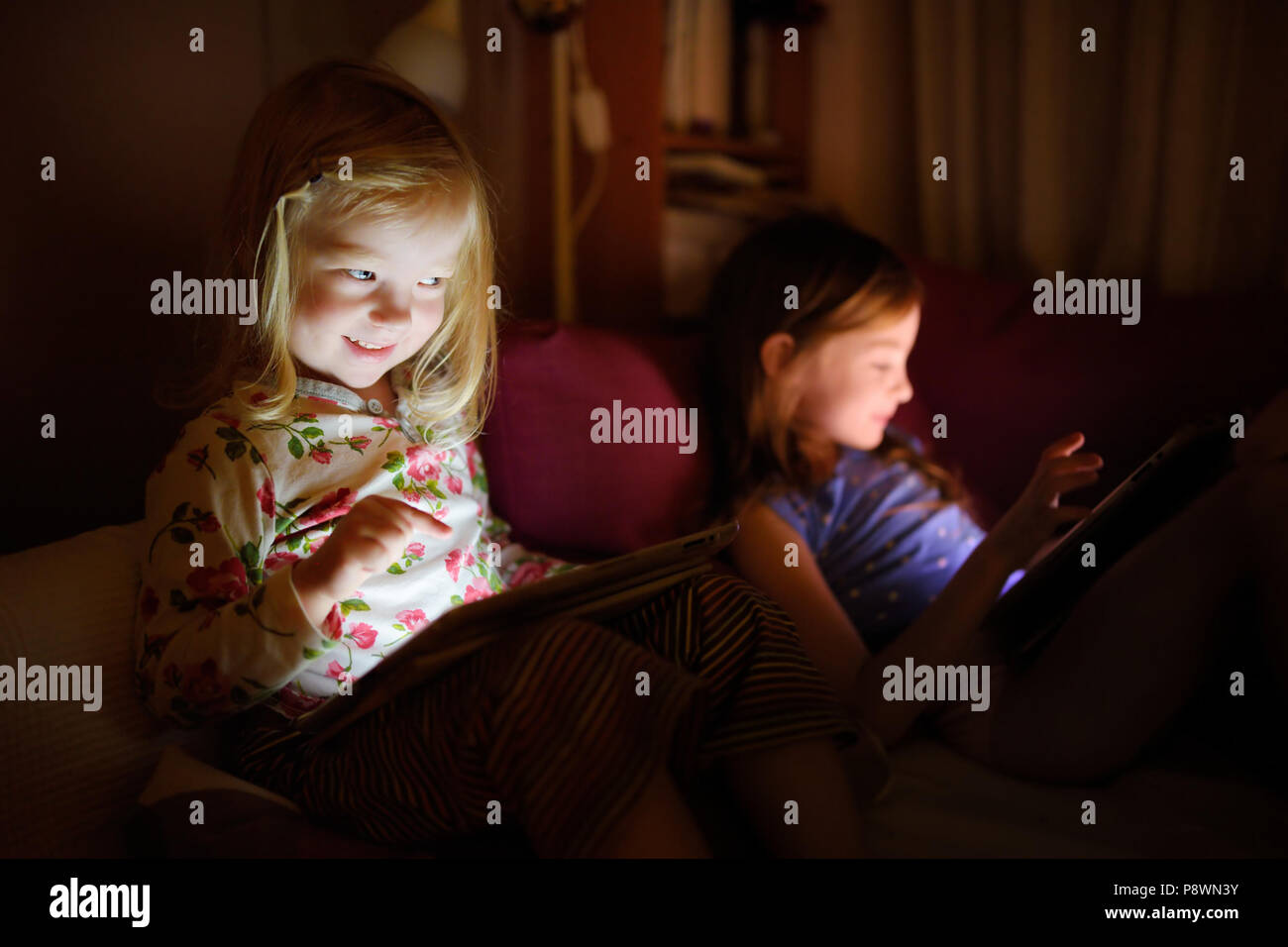 Two little sisters using digital tablet computer in a dark room Stock ...