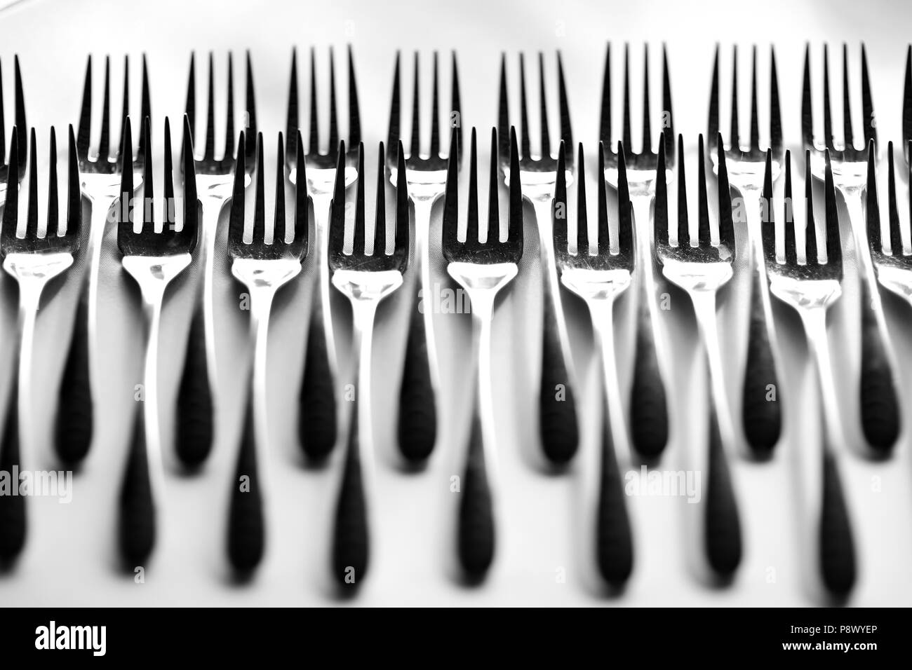 Row of forks on a white tablecloth Stock Photo