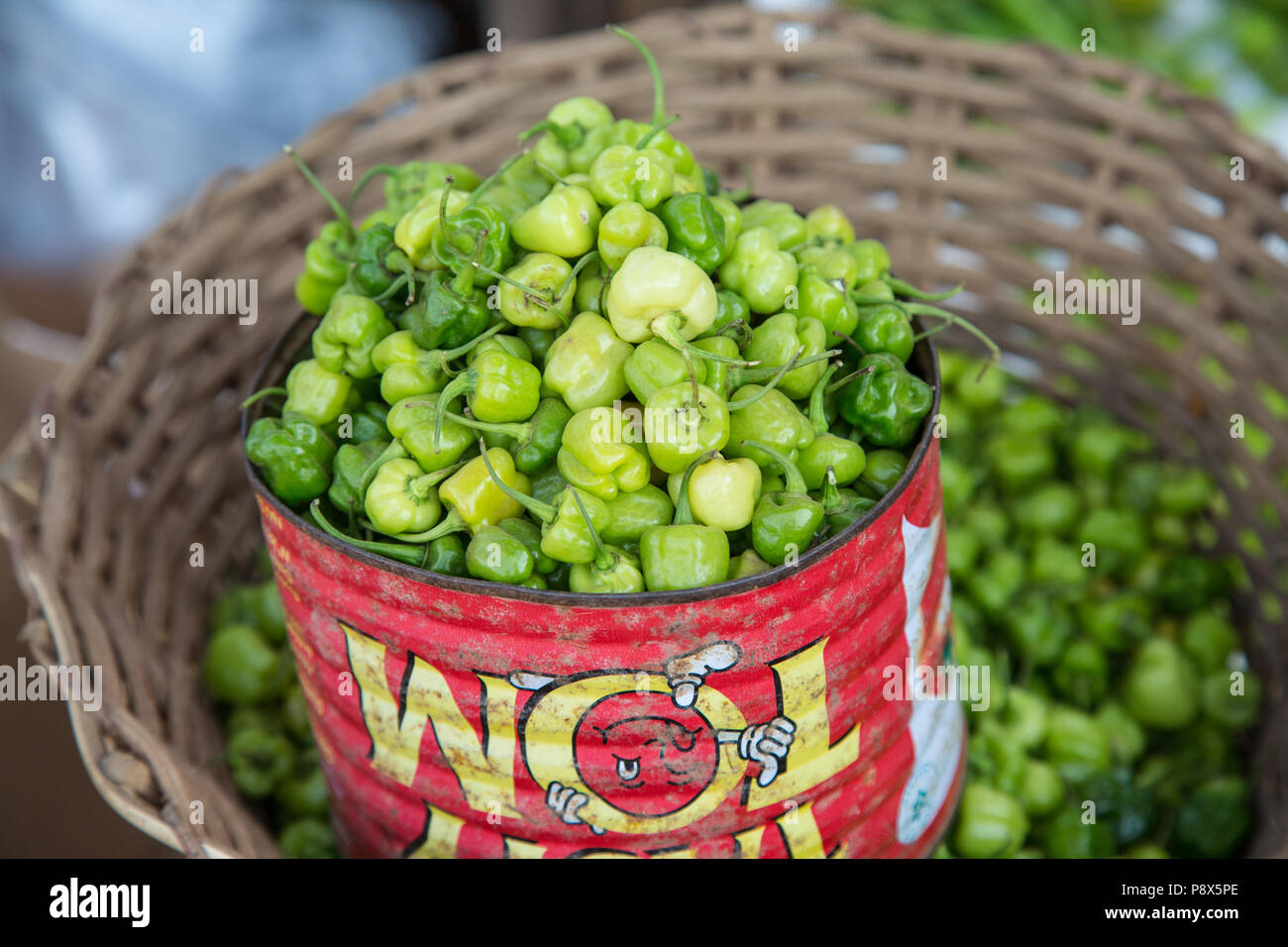Fresh green peppers in a metal tin for sale on market stall, Ghana Stock Photo