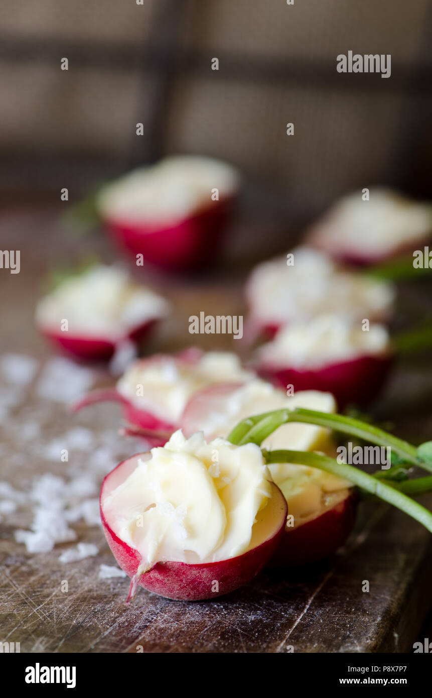 Radishes with unsalted butter and sea salt on the dark wooden background Stock Photo