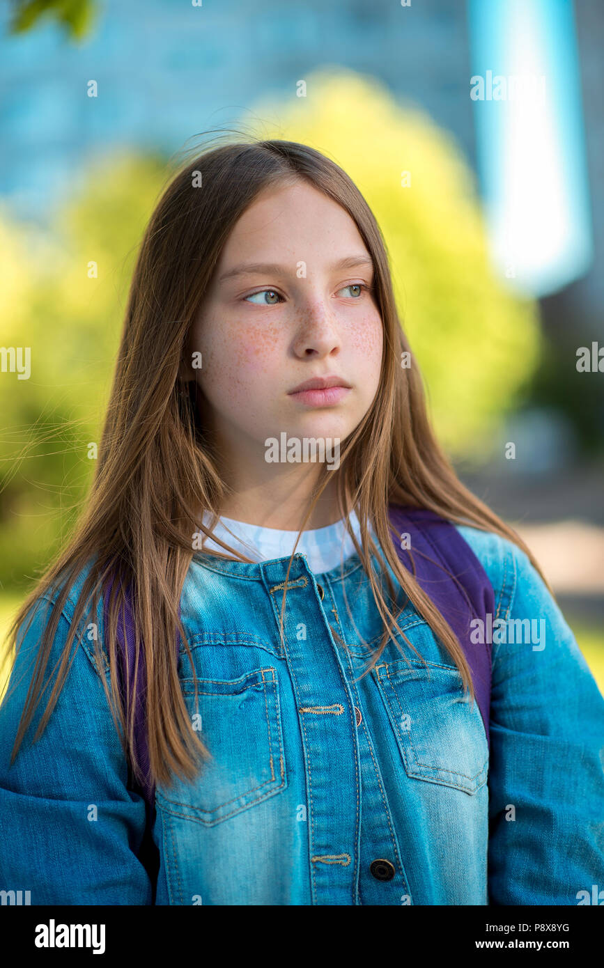 Closeup portrait of a schoolgirl girl. Summer in the city on nature