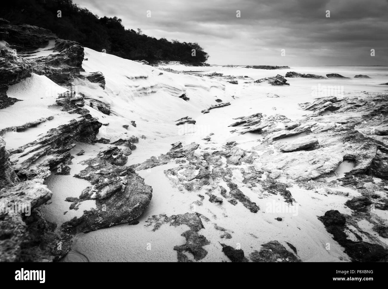Australian ocean landscape scenic at dawn with wet rocks on Stradbroke Island in black and white Stock Photo