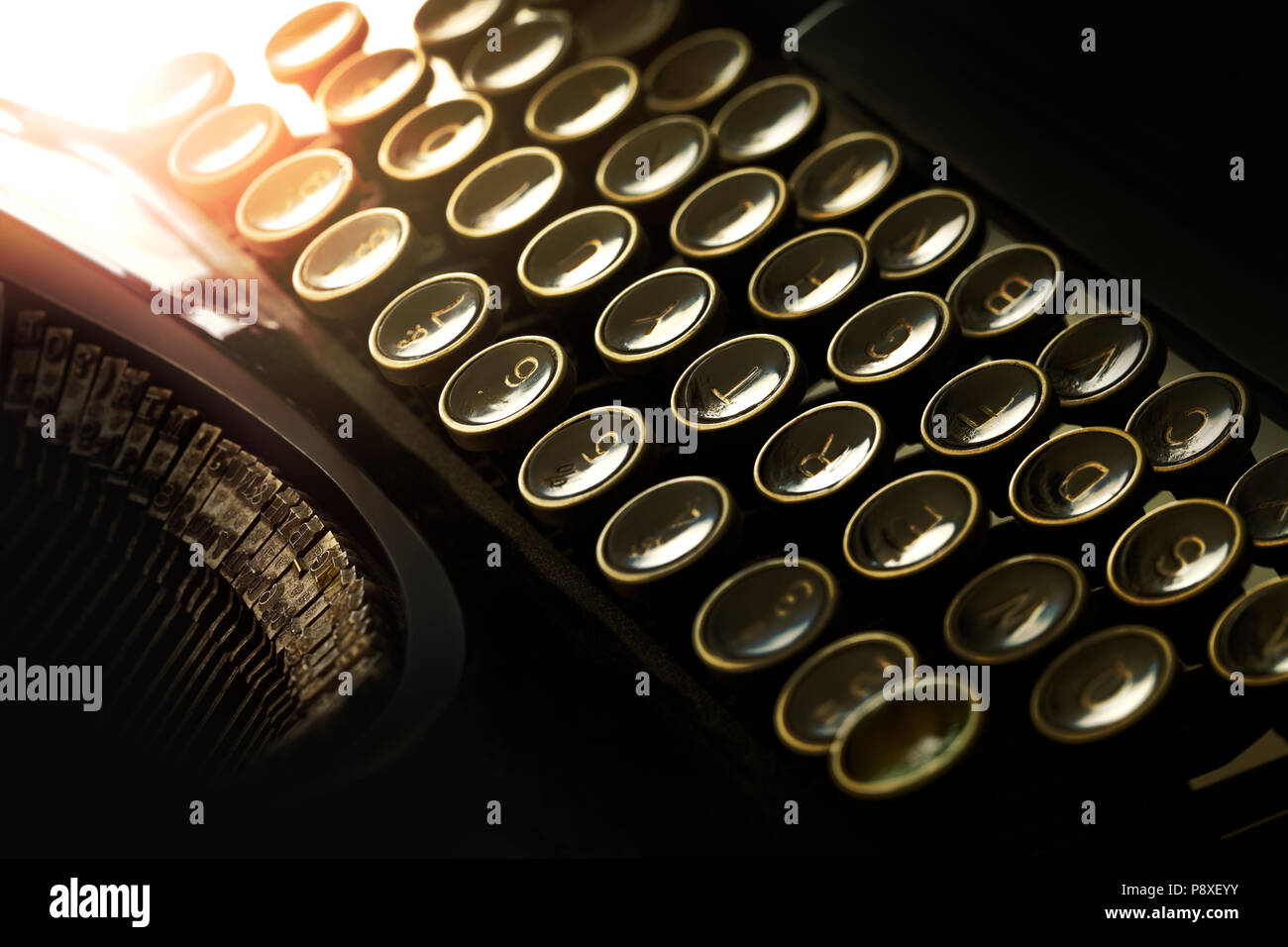 Detail of typewriter keyboard with warm toned backlight effect. Low key tone ambiance. Stock Photo