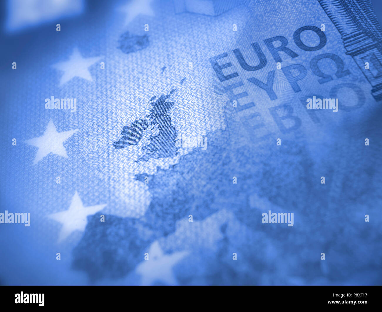 Shallow focus on euro banknote. Detail of Europe map with focus on Great Britain. Blue color tone. Stock Photo
