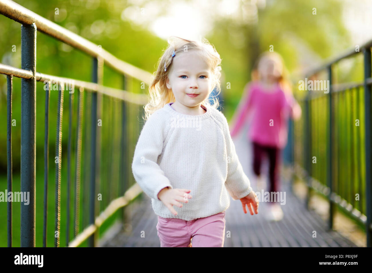 Two funny little girl jumping and running with joy and happiness outdoors on beautiful summer day Stock Photo