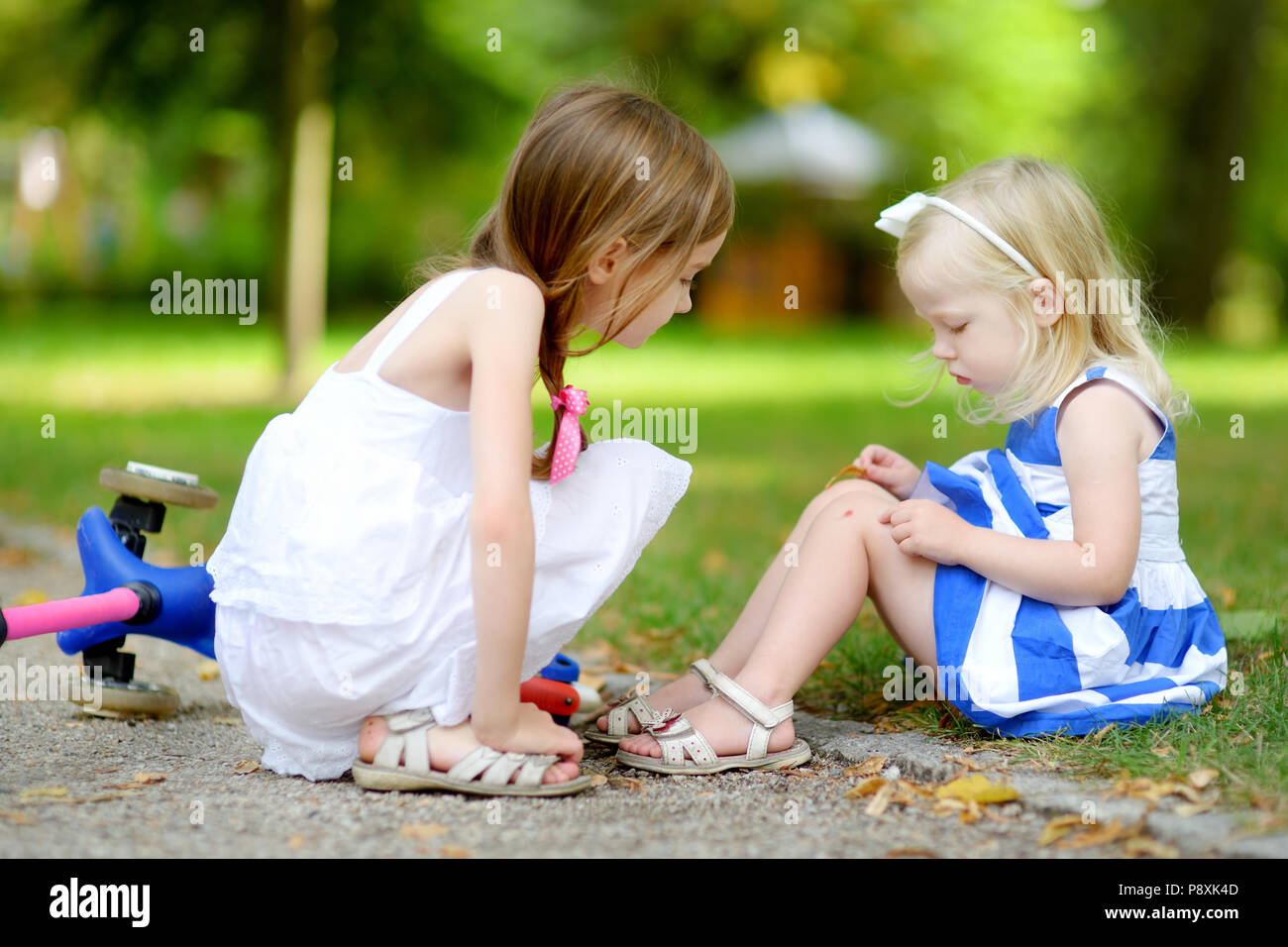 Little Girl Comforting Her Sister After She Fell While Riding Her Scooter At Summer Park Stock Photo Alamy
