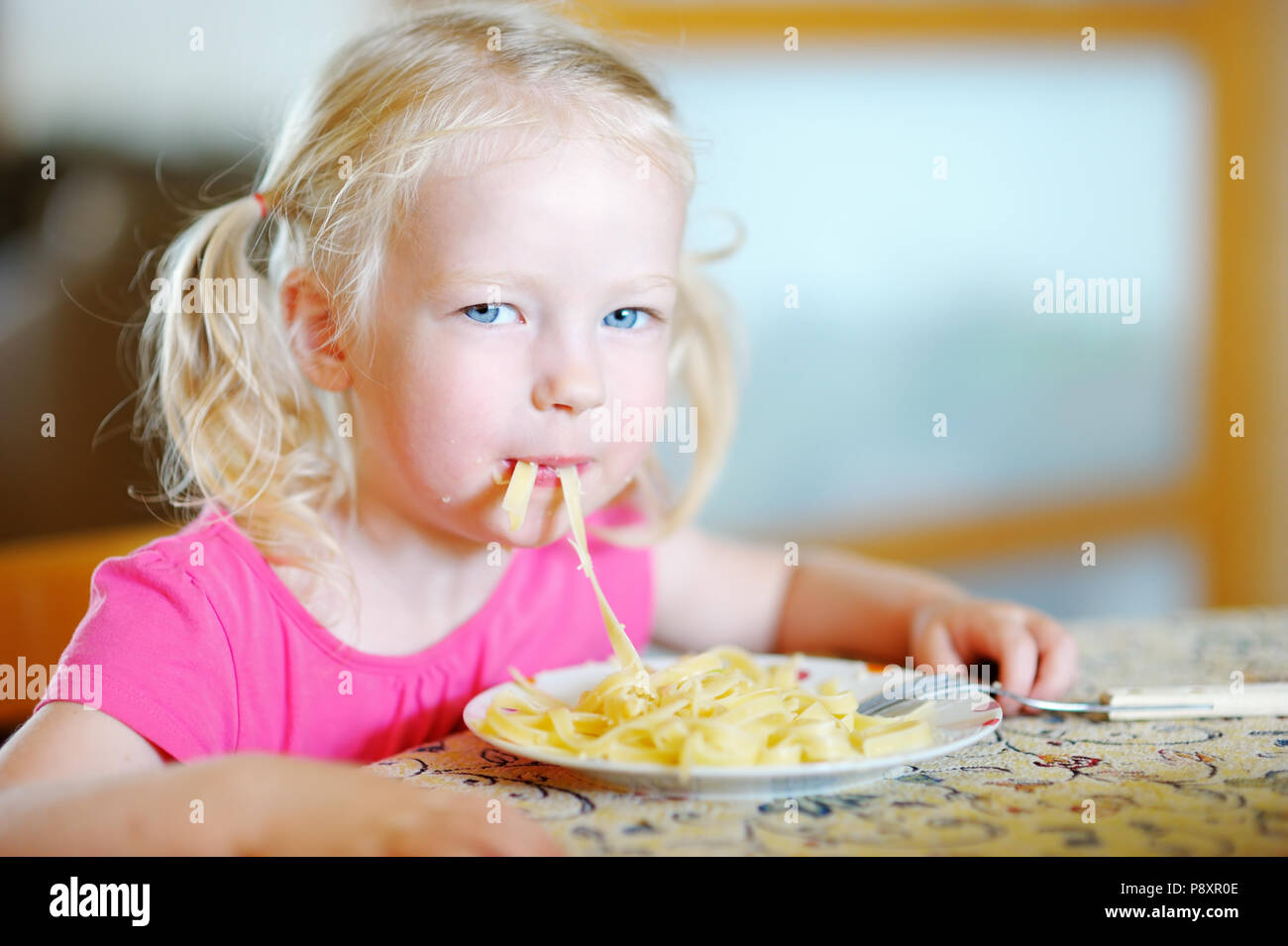 Cute funny little girl eating spaghetti at home Stock Photo - Alamy