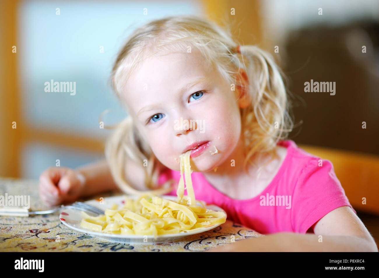 Cute funny little girl eating spaghetti at home Stock Photo - Alamy