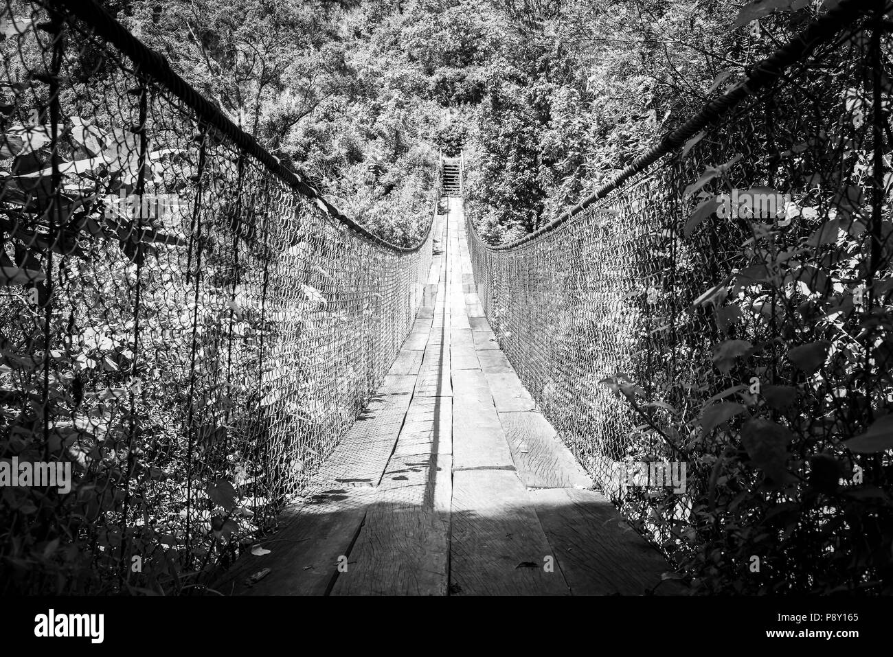 Wooden suspension bridge over river in Panajachel, Guatemala, Central America in black and white Stock Photo