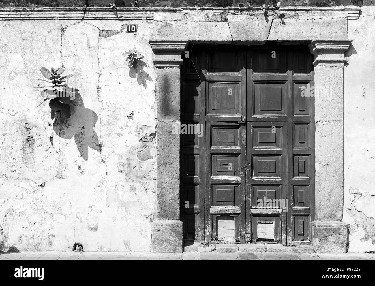 Wooden door in rustic blue spanish colonial wall, Antigua, Guatemala, Central America in black and white Stock Photo