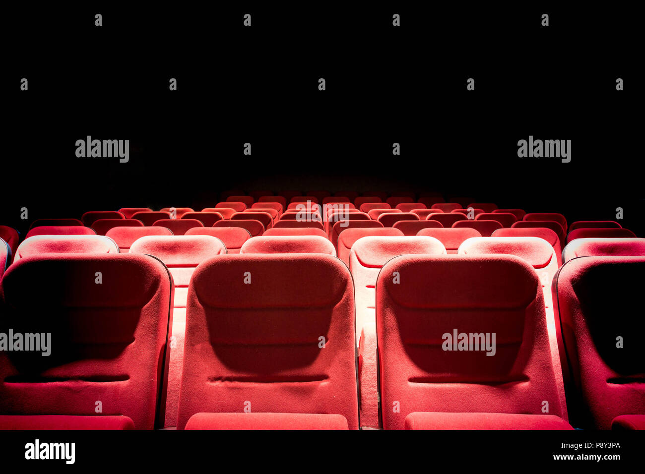 Dark movie theater with projection light and empty red seats Stock Photo