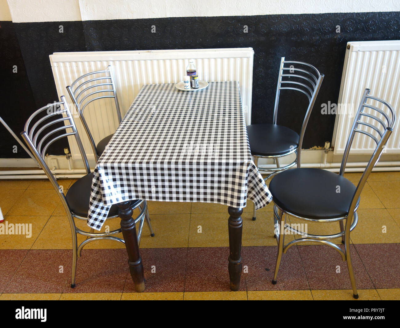 old fashioned style cafe table and chairs with checkered tablecloth Stock Photo