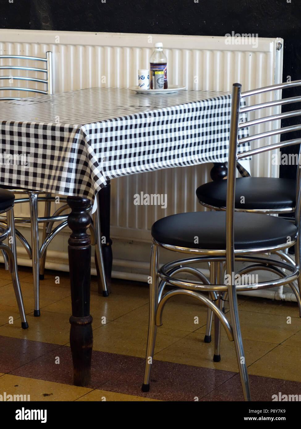 old fashioned style cafe table and chairs with checkered tablecloth