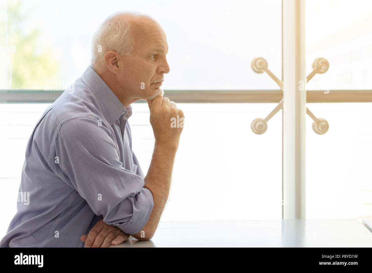 Profile view of Business man propping chin up with arm and staring straight ahead. Stock Photo
