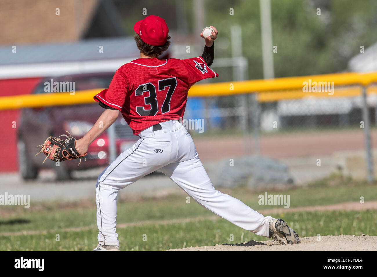 Pitcher delivering pitch, in full stride, showing grip, boys afternoon