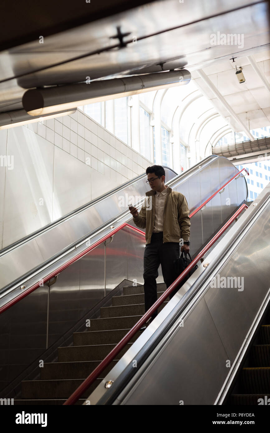 Man using mobile phone while moving downstairs Stock Photo