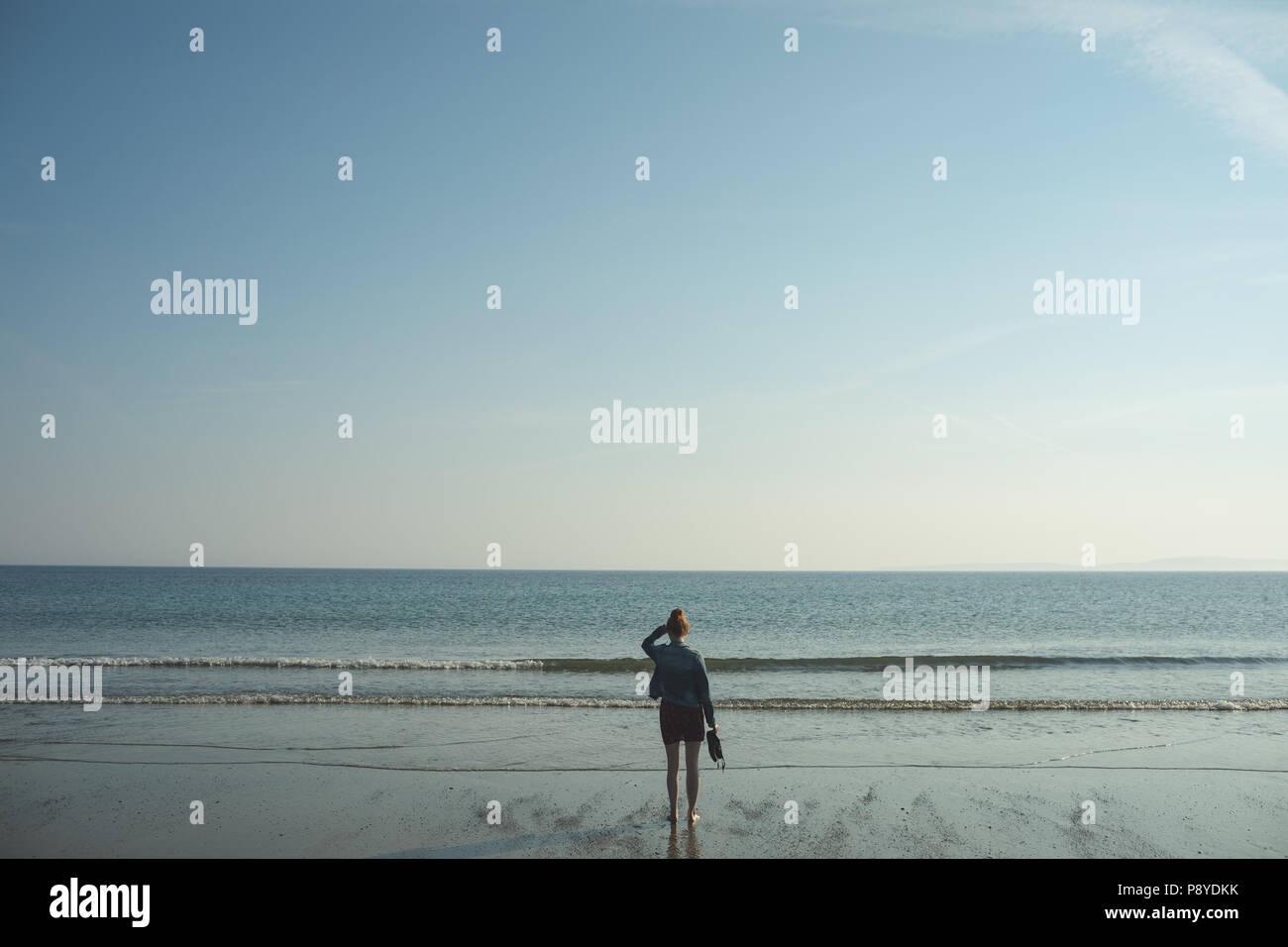 Woman standing on beach looking at sea hi-res stock photography and ...