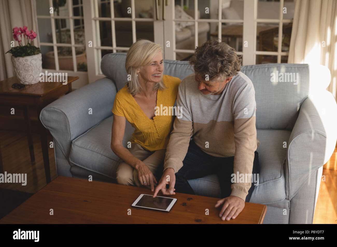 Senior couple using digital tablet on sofa Stock Photo