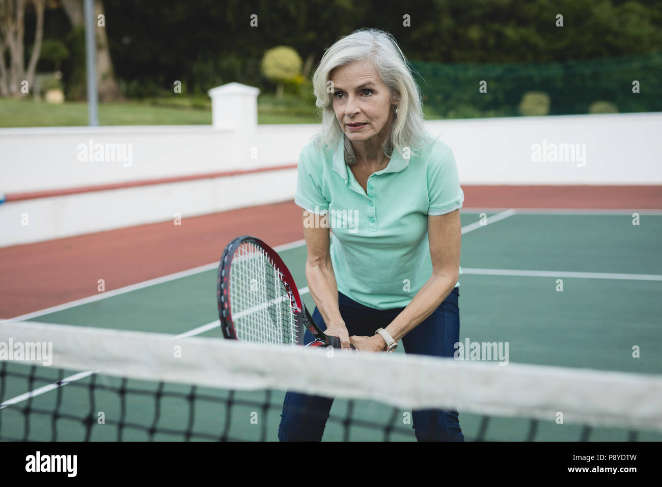 Senior woman playing tennis in tennis court Stock Photo