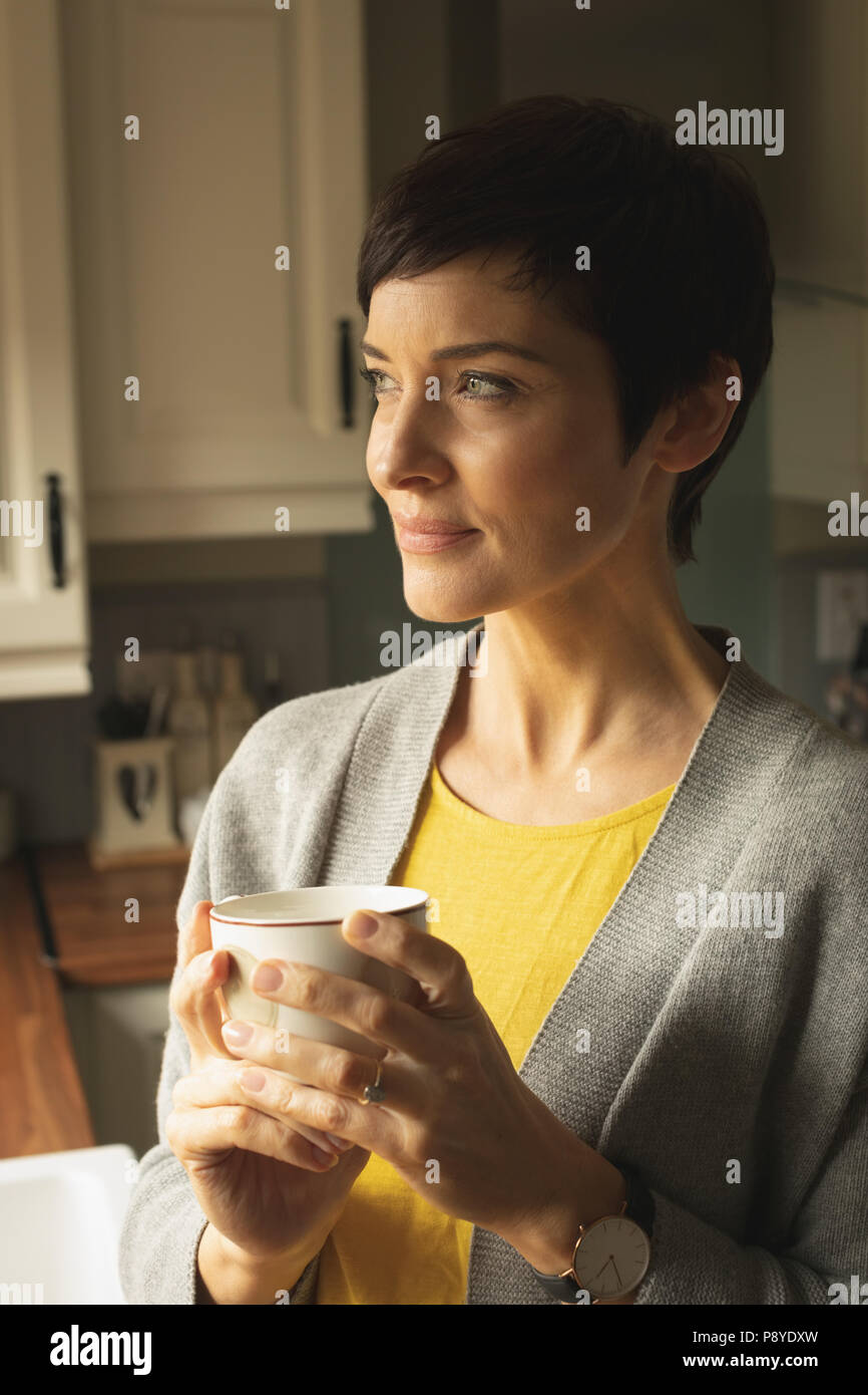 Thoughtful woman having coffee in the kitchen at home Stock Photo