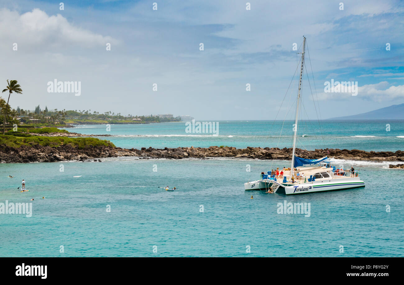 People swim and snorkel from a catamaran sailing trip off the coast of Maui. Tourist activity. Stock Photo